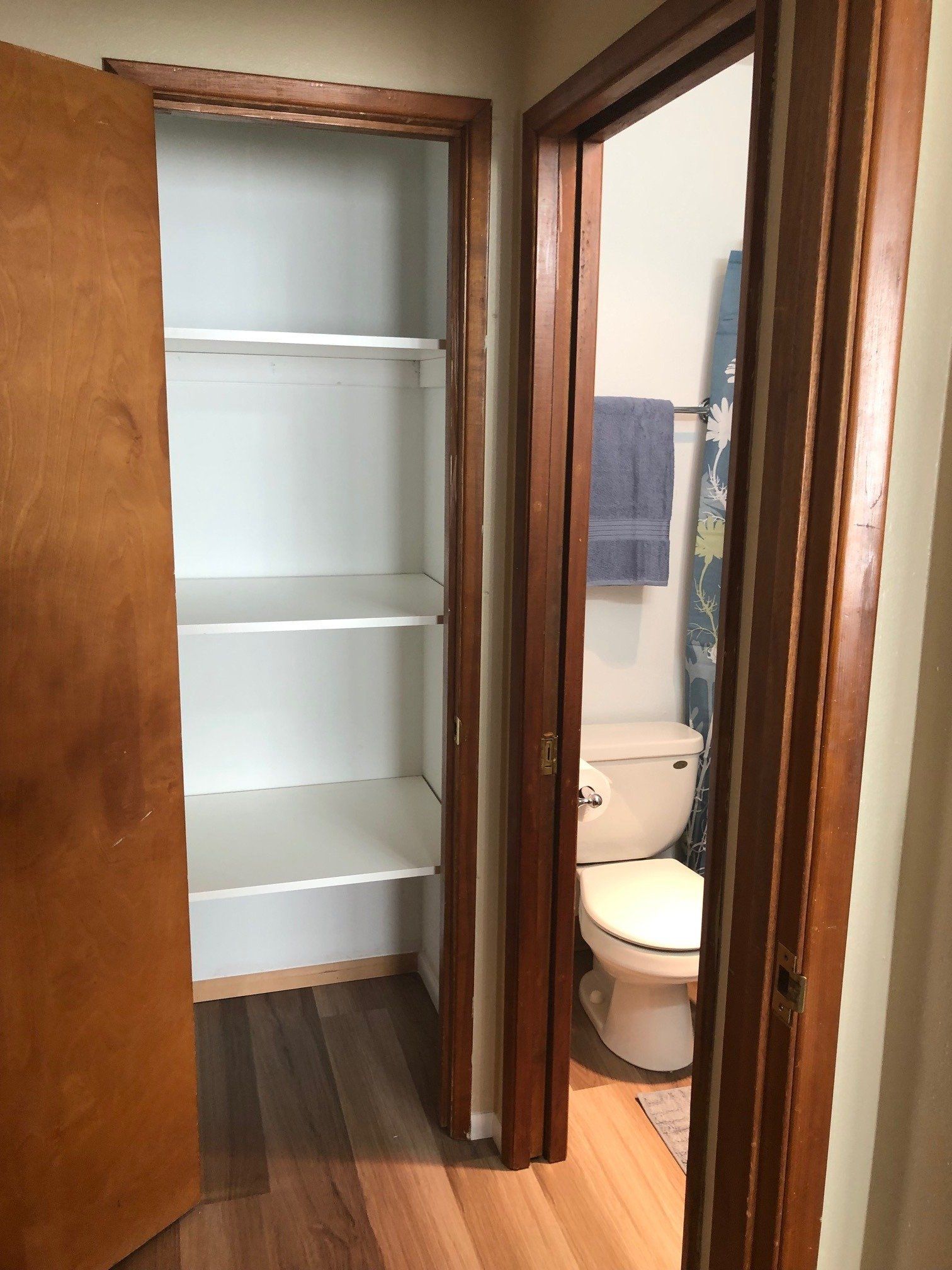 A bathroom with a toilet and a closet with shelves