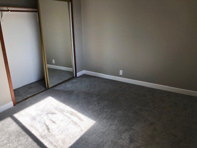 An empty bedroom with a large mirror on the wall