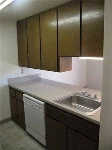 A kitchen with brown cabinets and a white dishwasher