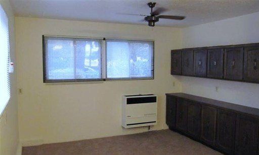 An empty living room with a ceiling fan and a heater.