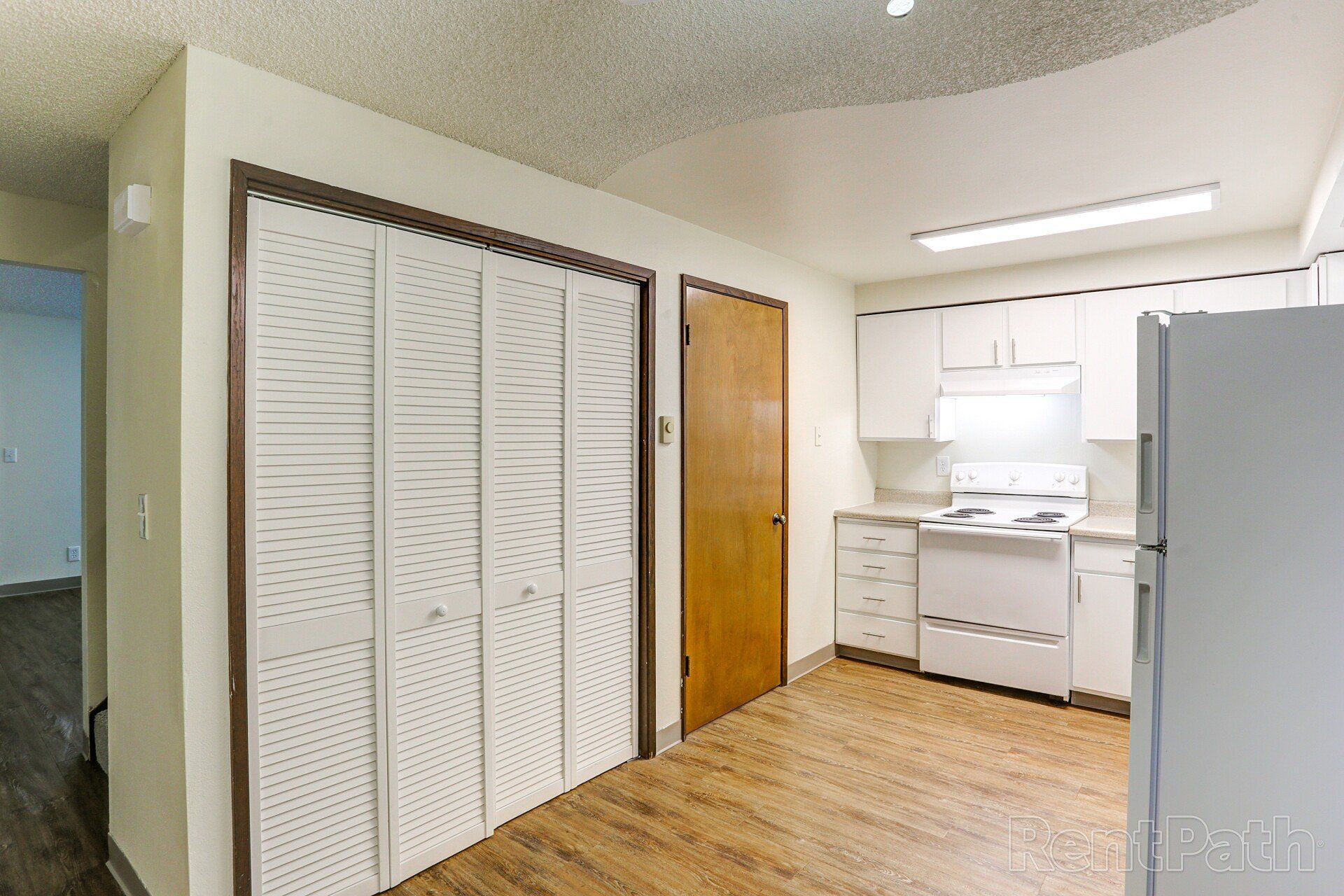 A kitchen with white cabinets and a white refrigerator