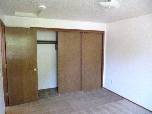 An empty bedroom with a closet and a ceiling fan