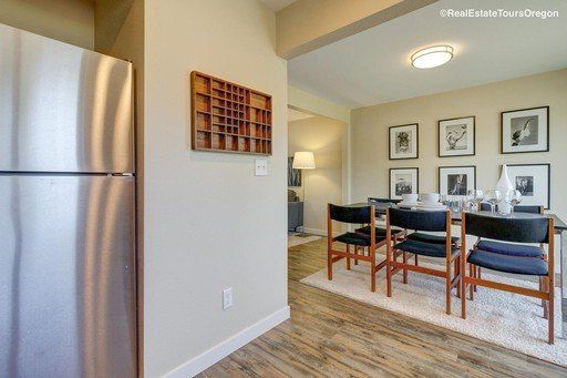 A kitchen with a stainless steel refrigerator and a dining room with a table and chairs.