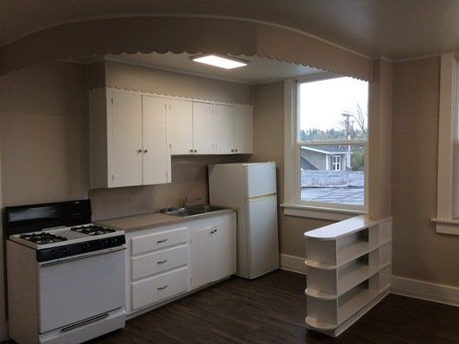 A kitchen with a stove a refrigerator and a window