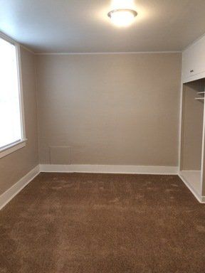 An empty room with a brown carpet and a window.