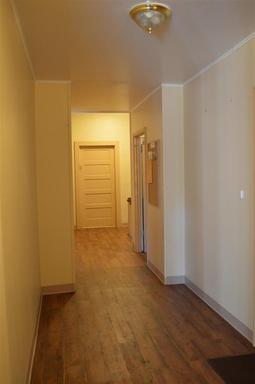 An empty hallway with hardwood floors and white walls in a house.