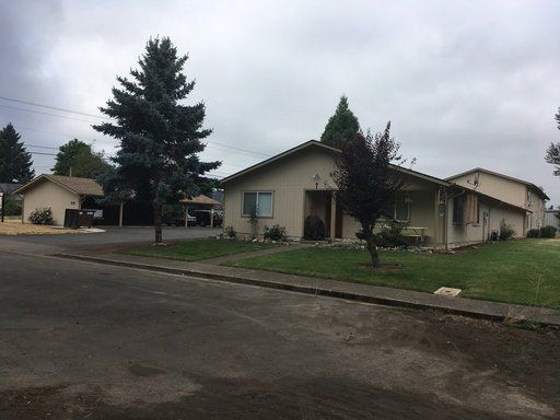 A row of houses with trees in front of them on a cloudy day