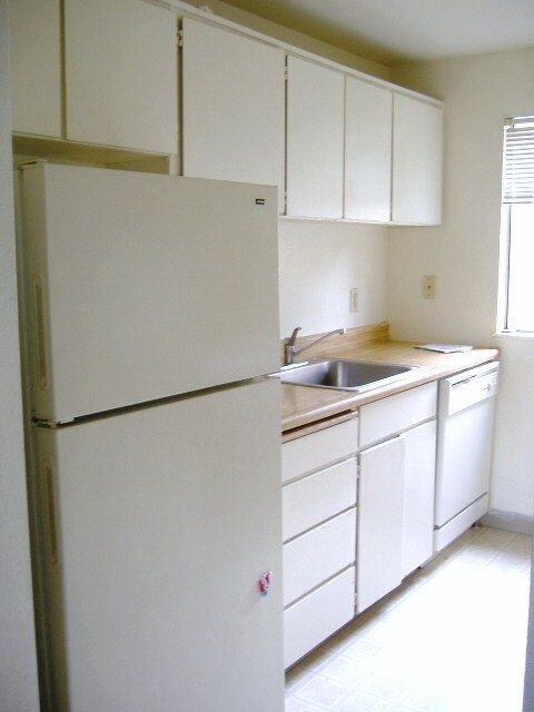 A kitchen with white cabinets and a white refrigerator