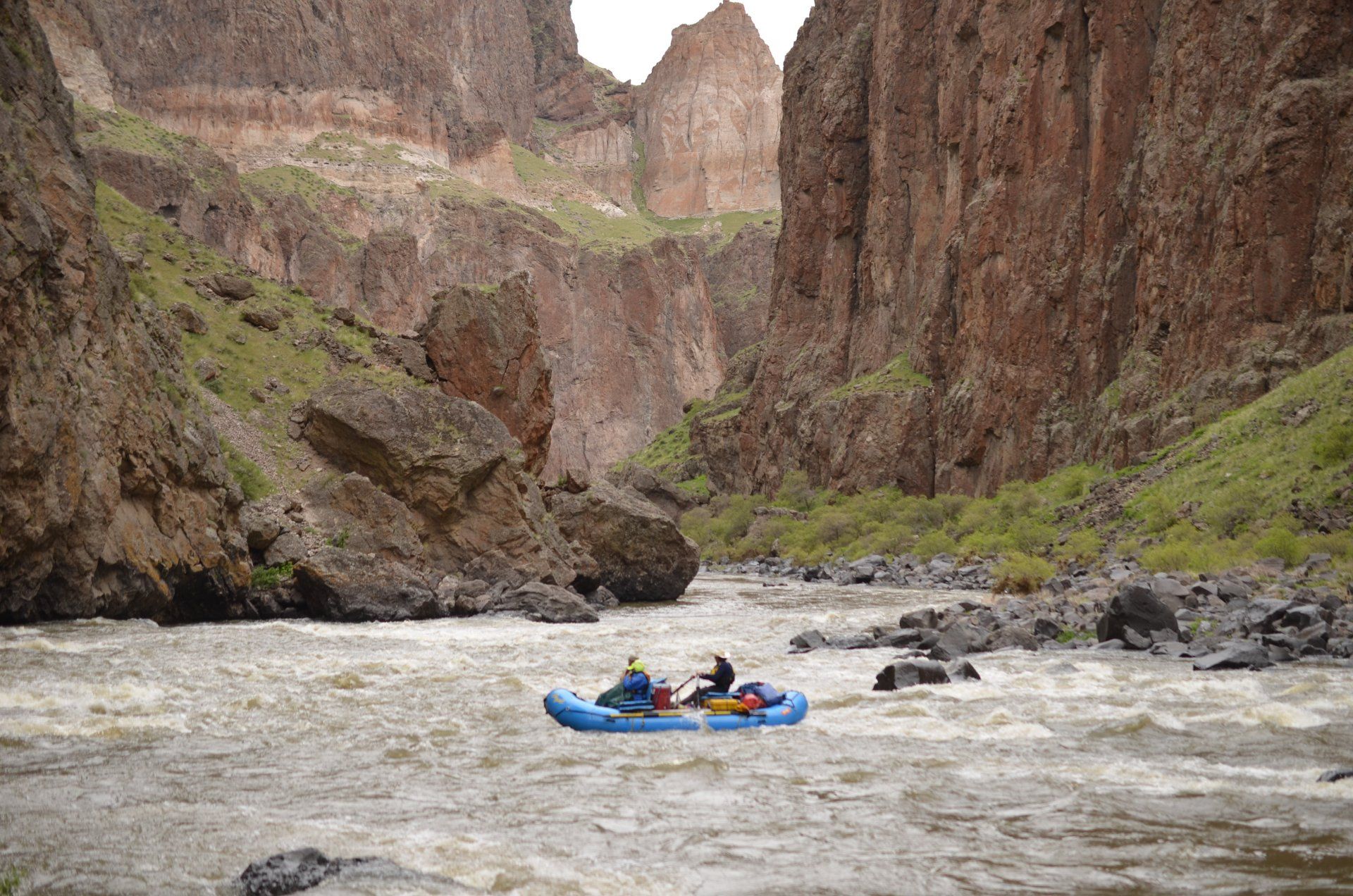 Towering canyon walls frame an Ouzel raft navigating Montgomery Rapid on the Owyhee River.