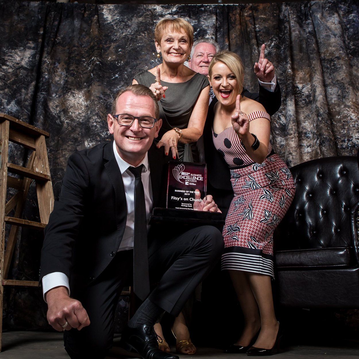 A group of people posing for a picture with a man holding a trophy
