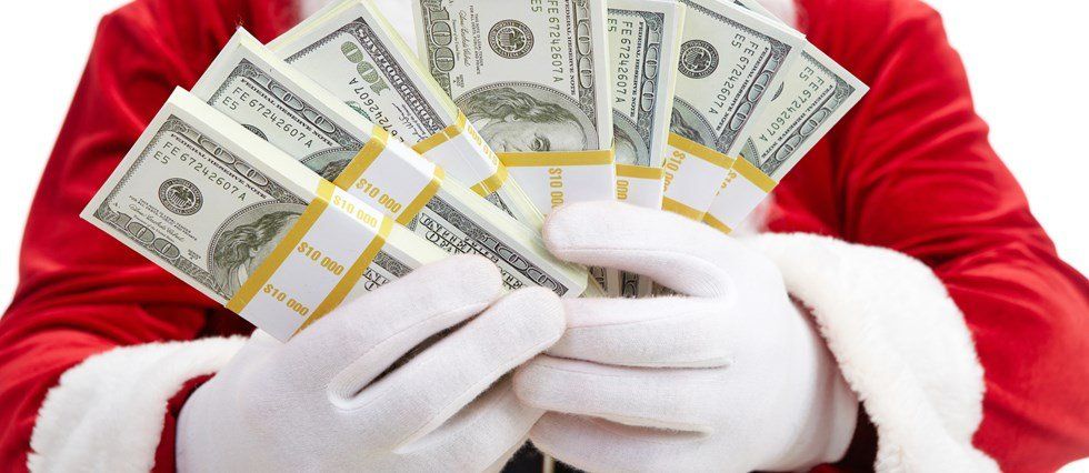 Santa claus is holding stacks of money in his hands