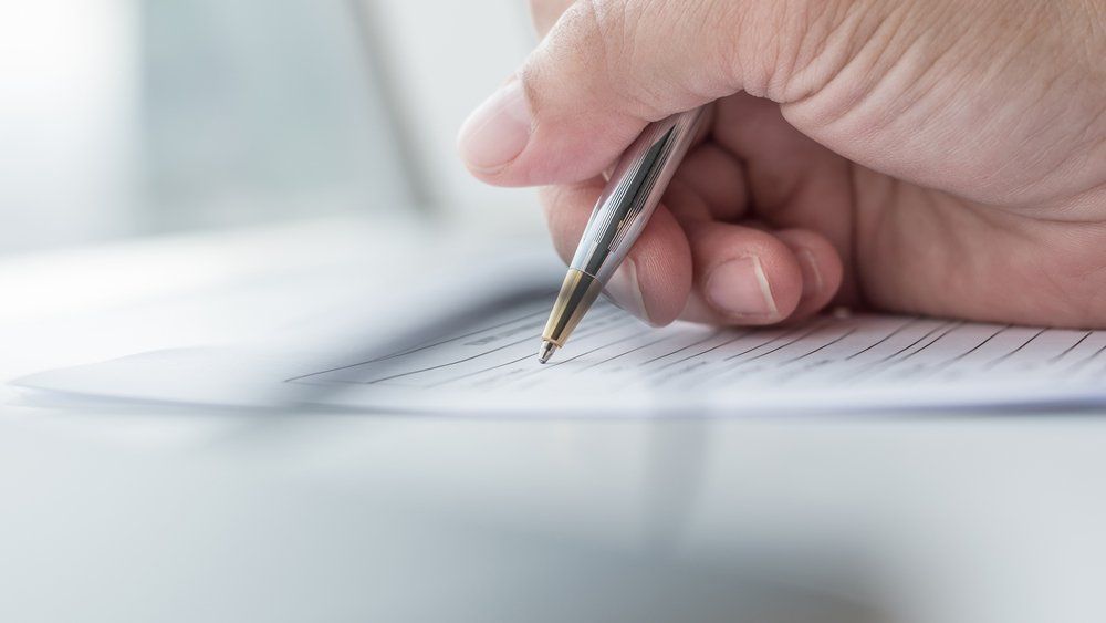 person writing on document with pen