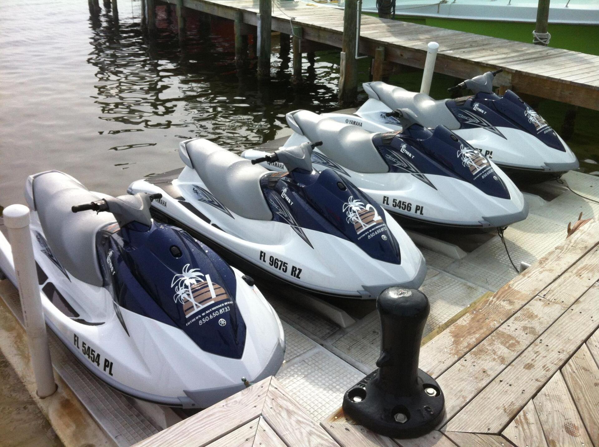 4 blue and white jet skis tied to dock at Luther's Rentals