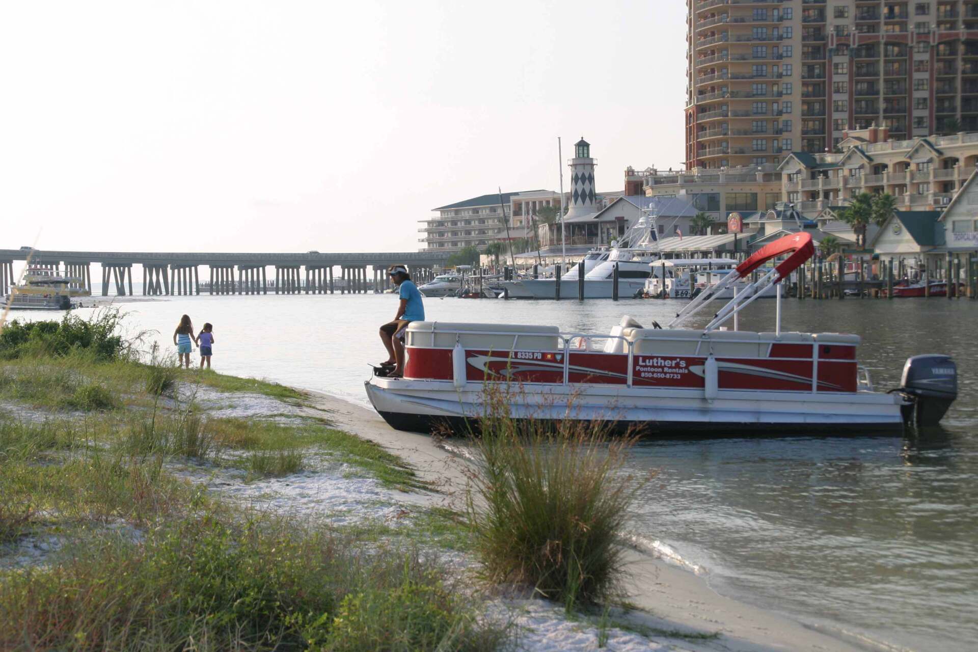 Man sitting on red pontoon boat rental anchored on Destin FL beach
