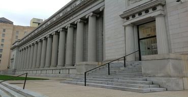 Large stone neoclassical building with columns and steps at the entrance.