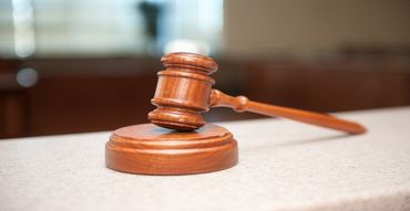 Wooden judge’s gavel resting on its round base on a courtroom desk
