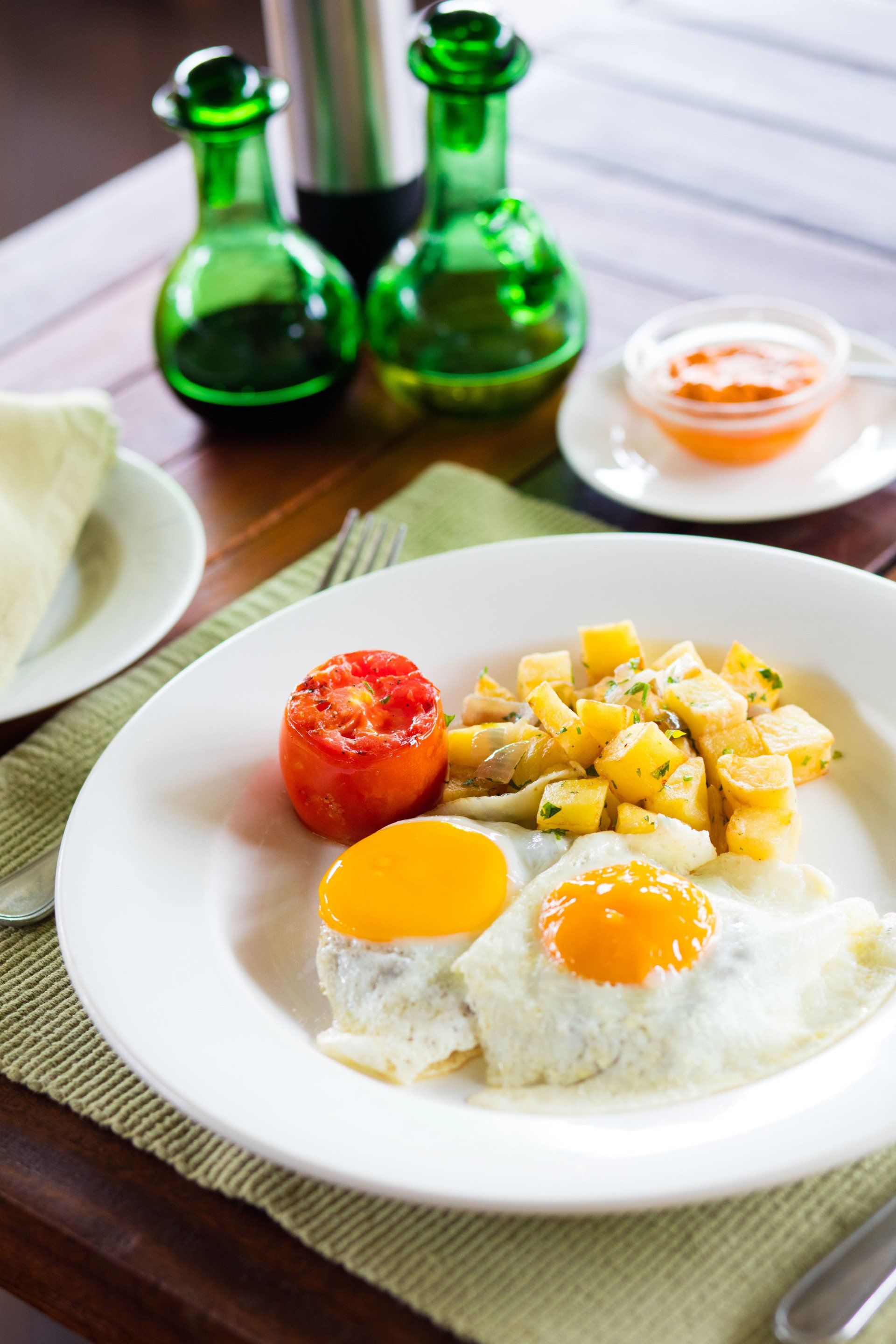 A plate of food with eggs , potatoes and tomatoes on a table.