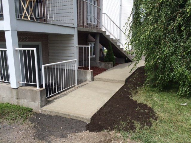 Une passerelle en béton menant à une maison avec des escaliers