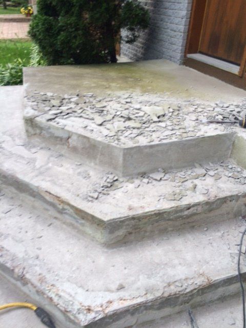 Un escalier en béton est en train d'être démoli devant une maison.