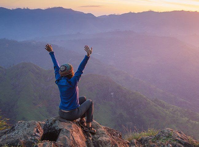 Woman in mountains celebrating the sunrise.