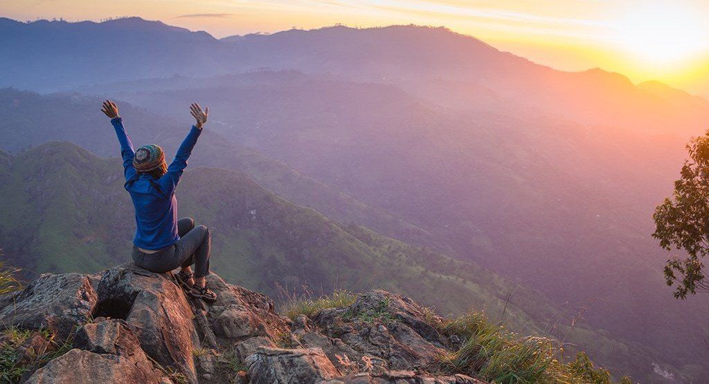 Woman celebrating the sunrise in the mountains. Massage helps your muscles get to places like this!