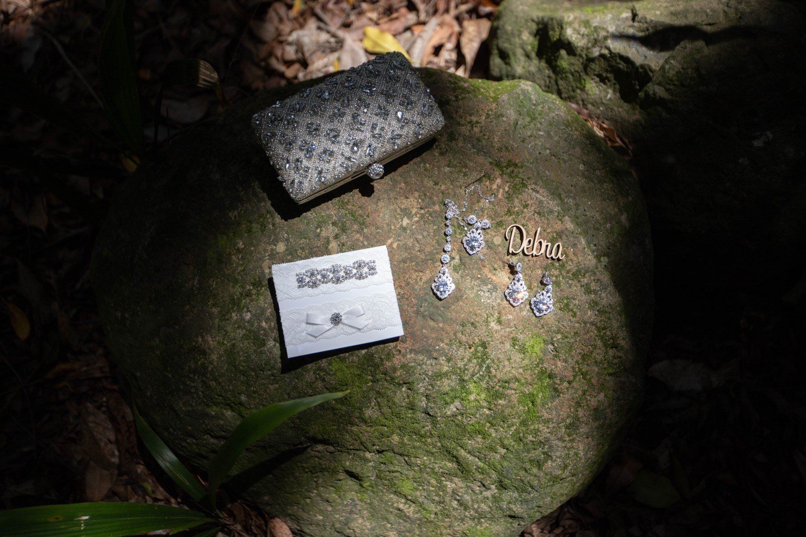 a pair of earrings and a purse are sitting on a rock .