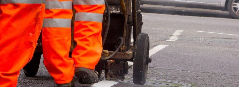 Men in fluorescent trousers painting a road