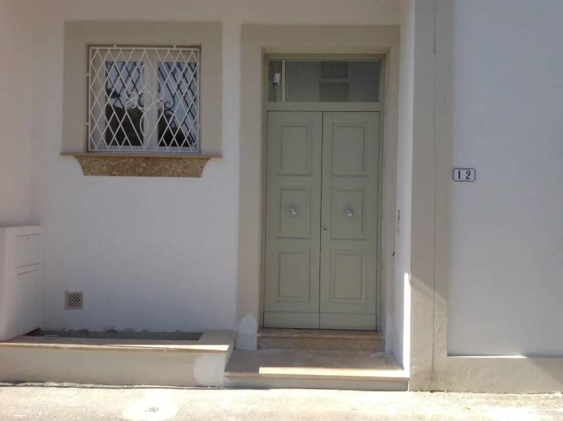Una casa bianca con una porta verde e una finestra.