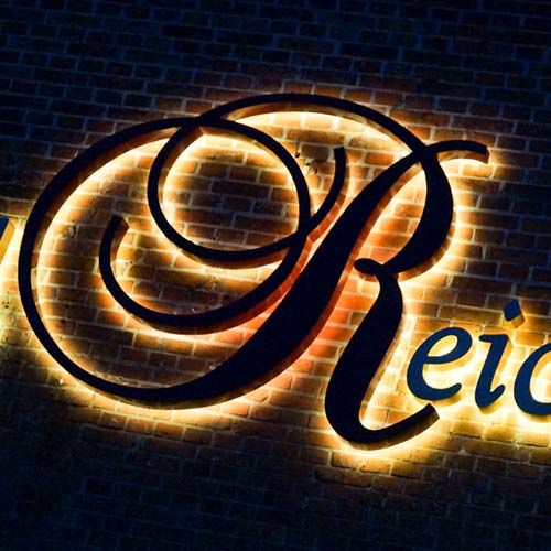 Das Wort „Reid“ leuchtet auf einer Ziegelwand