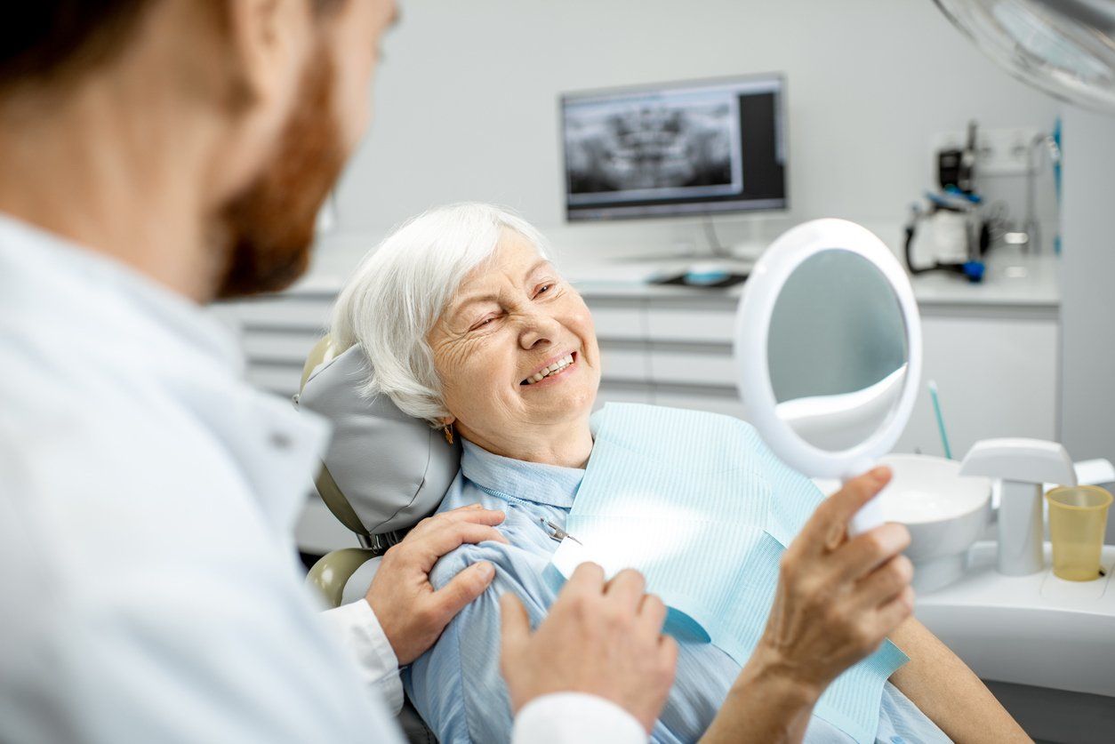 older woman getting dentures at dentist office