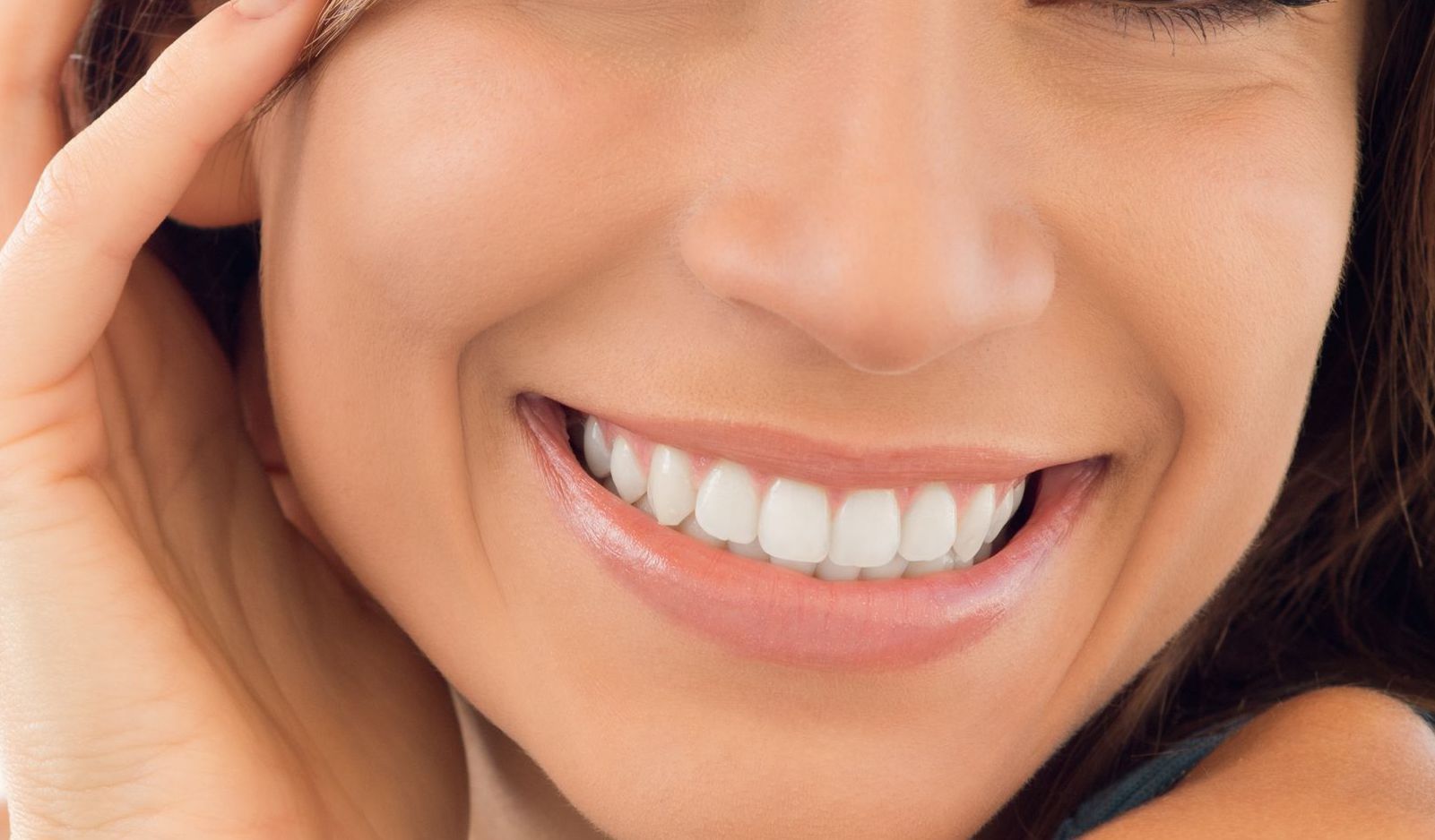 Close-up of a smiling person with white teeth and dark hair.