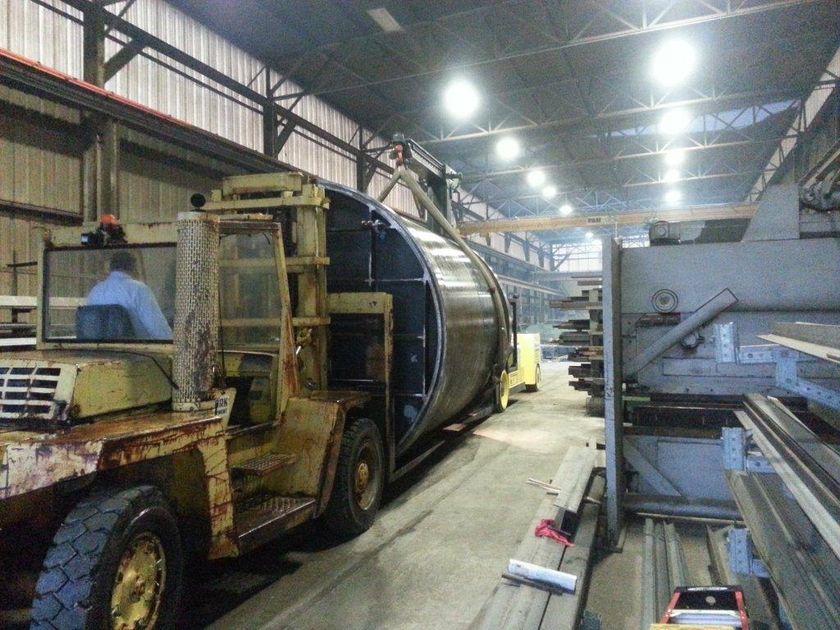 A man is driving a forklift in a factory.