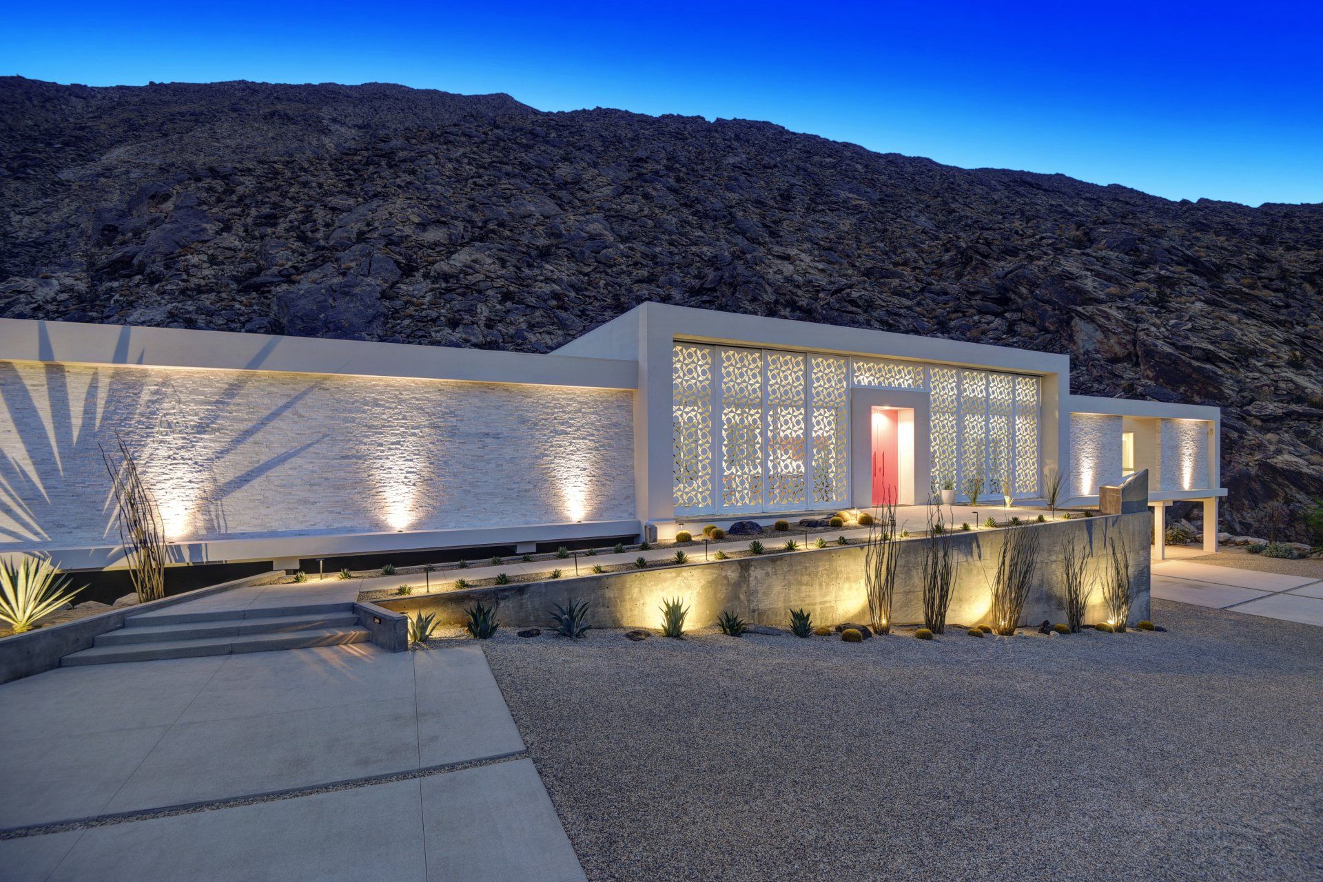 A modern white house with a red door is sitting on top of a hill.