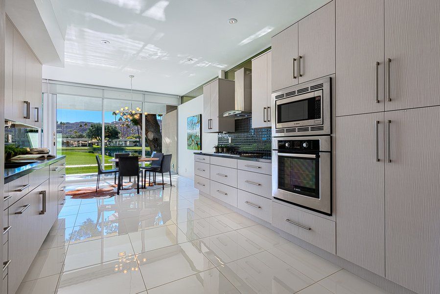 A kitchen with white cabinets and stainless steel appliances and a dining room in the background.