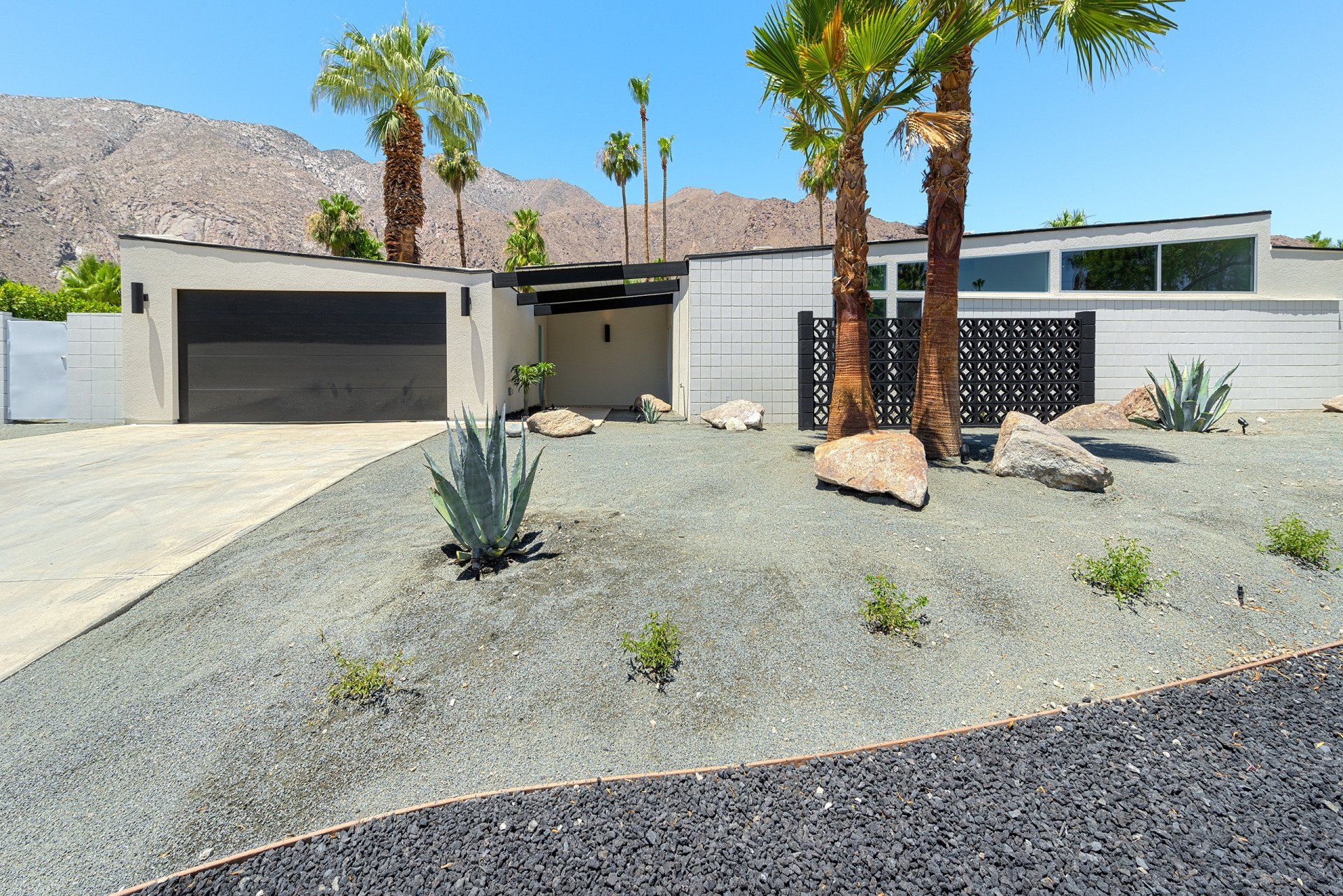 A house with a garage and palm trees in front of it