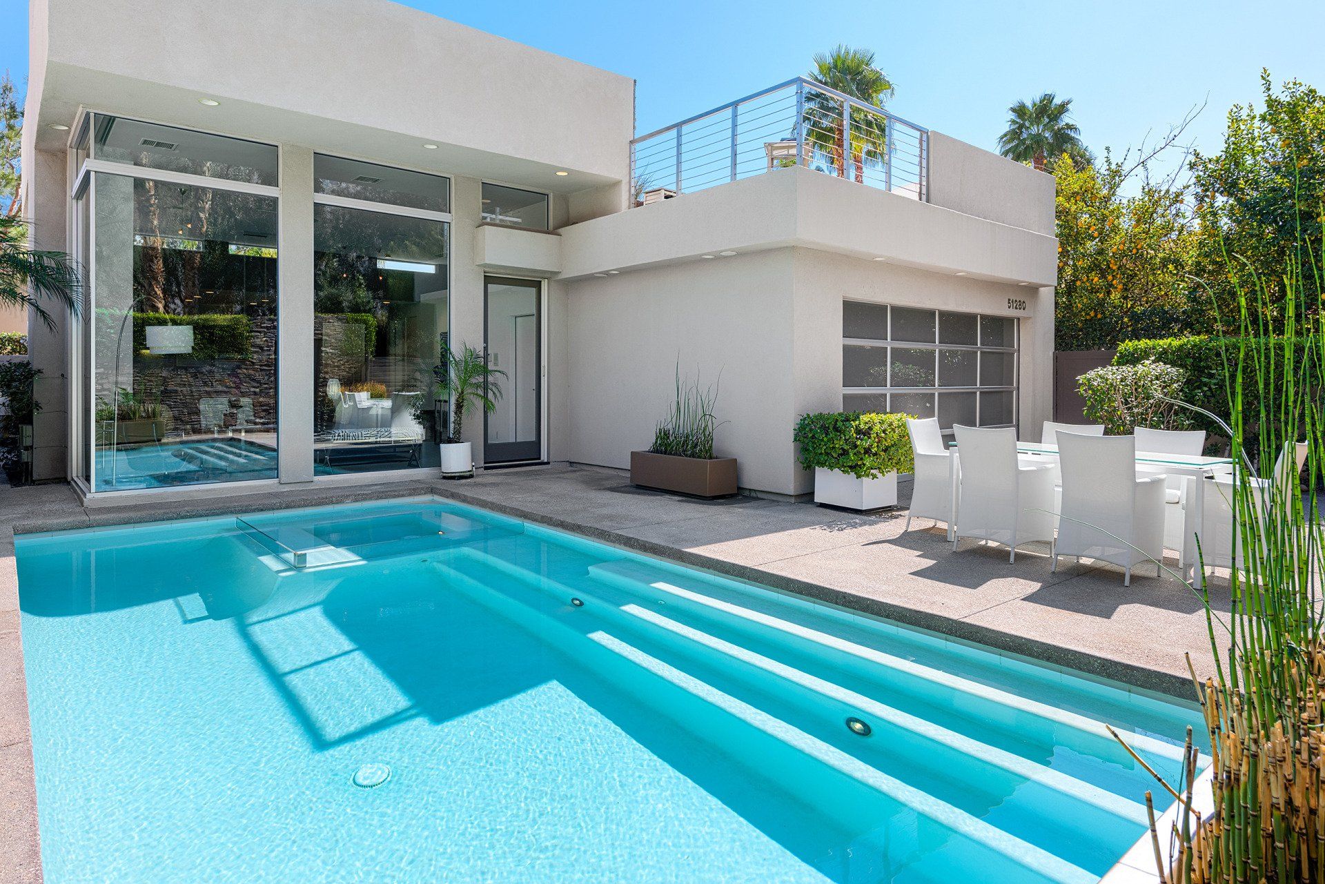 A white house with a large swimming pool in front of it