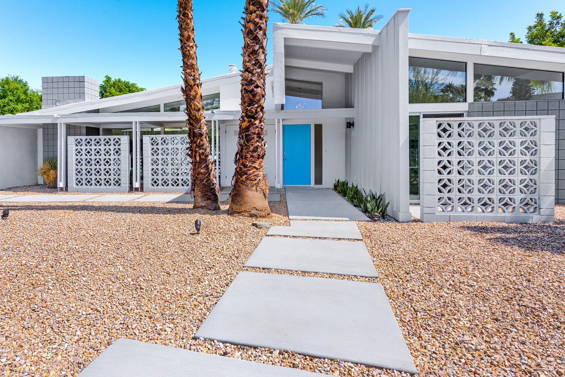 A white house with a blue door and palm trees in front of it