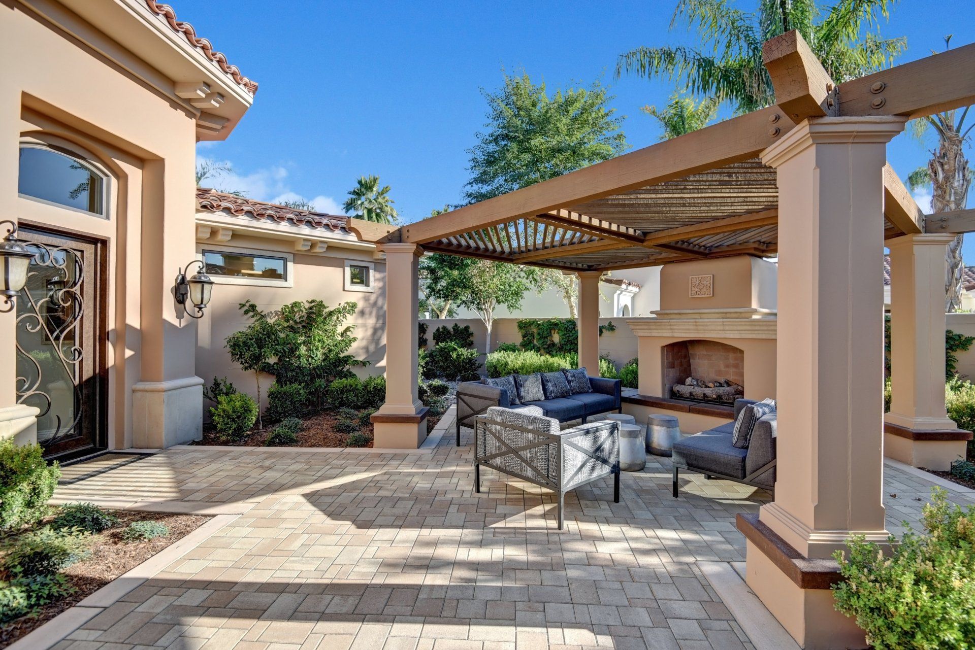 A patio with a pergola and a fireplace