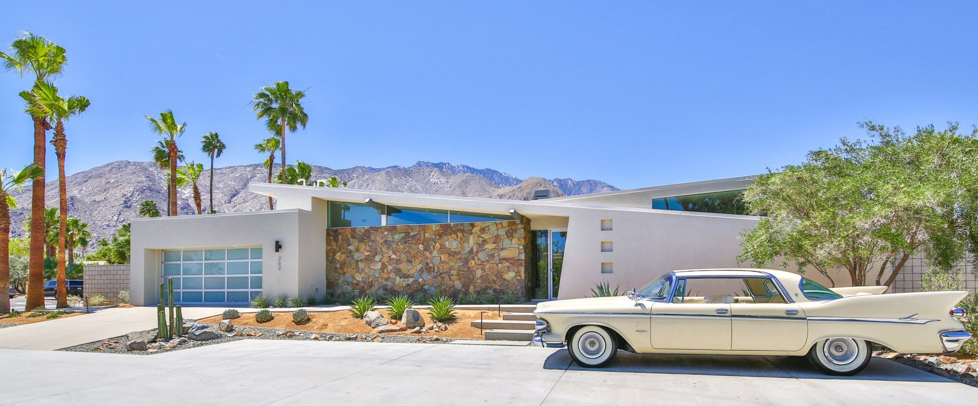 A white car is parked in front of a modern house.
