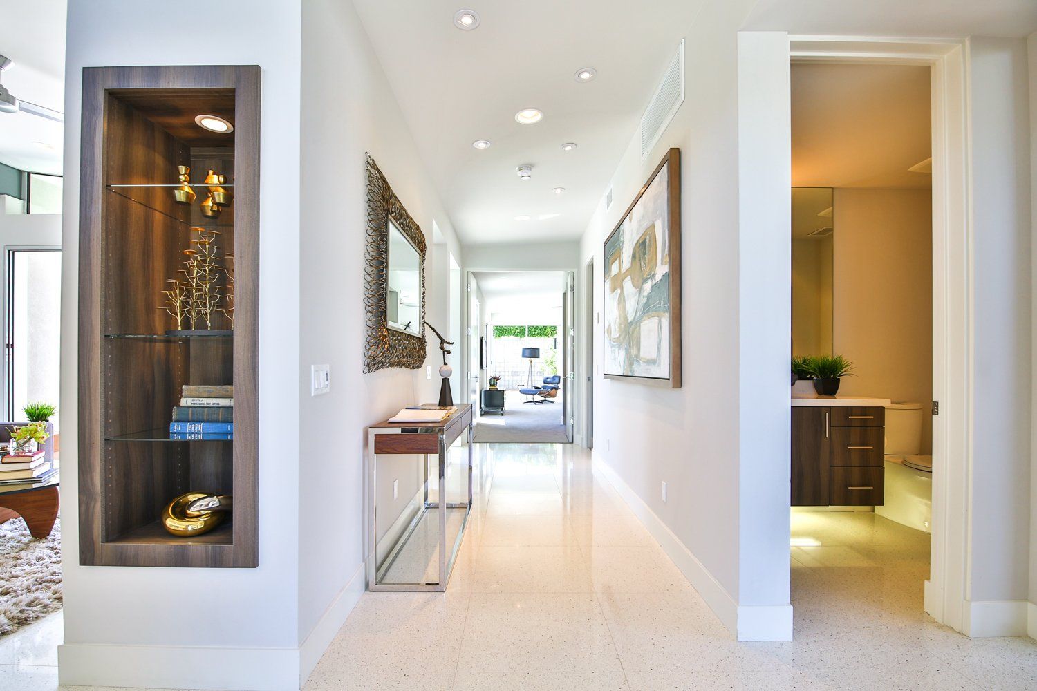A long hallway in a house with a table and a mirror on the wall.