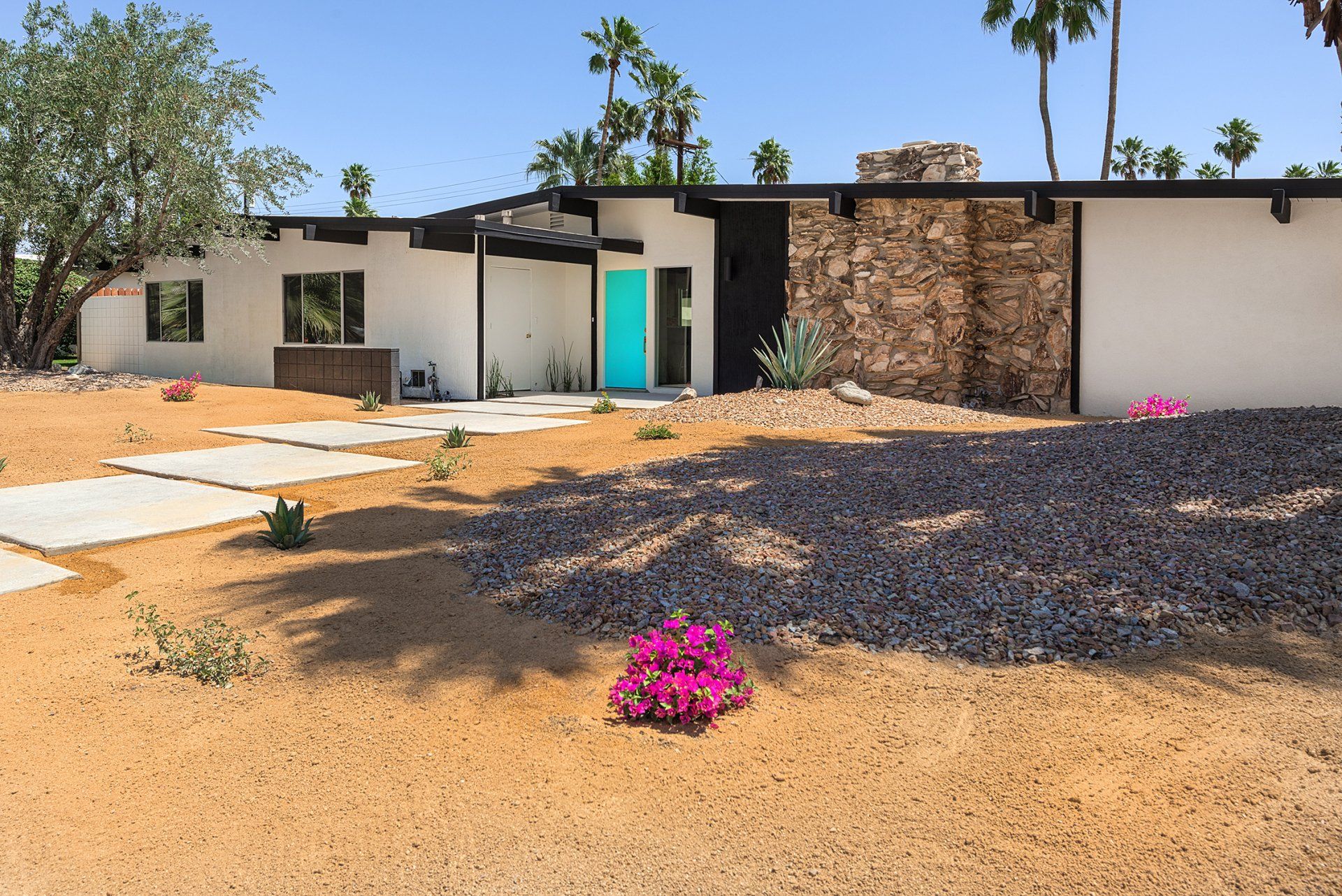 A white house with a blue door and a stone wall