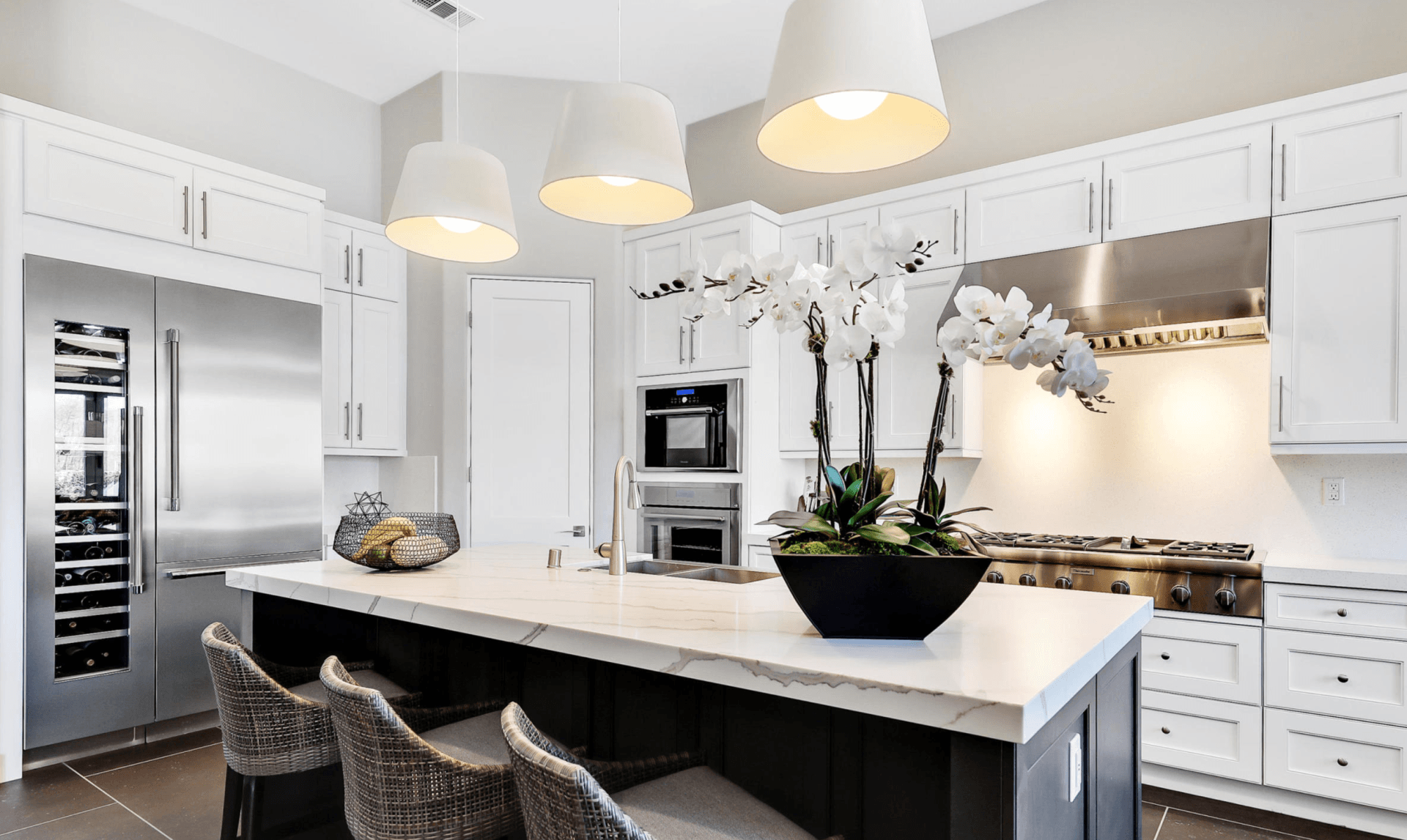 A kitchen with white cabinets , stainless steel appliances , and a large island.