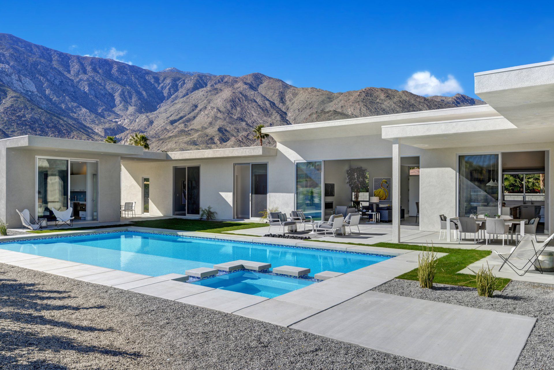 A modern house with a large swimming pool in front of it.
