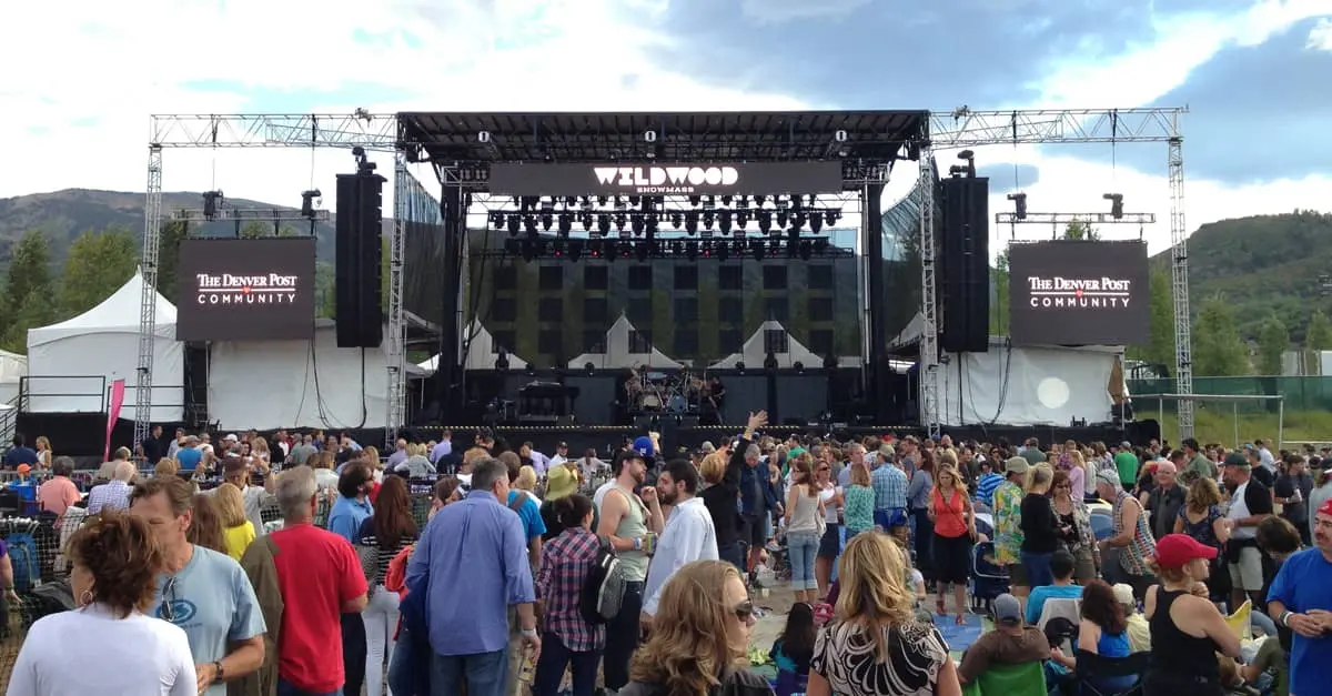A crowd of people are standing in front of a stage at a concert.