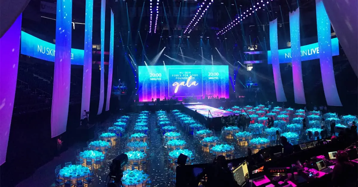 A large room filled with tables and chairs with a stage in the background.