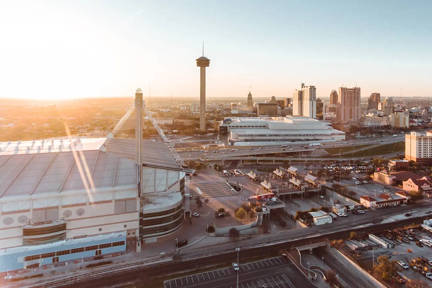 An aerial view of a city at sunset with a stadium in the foreground.