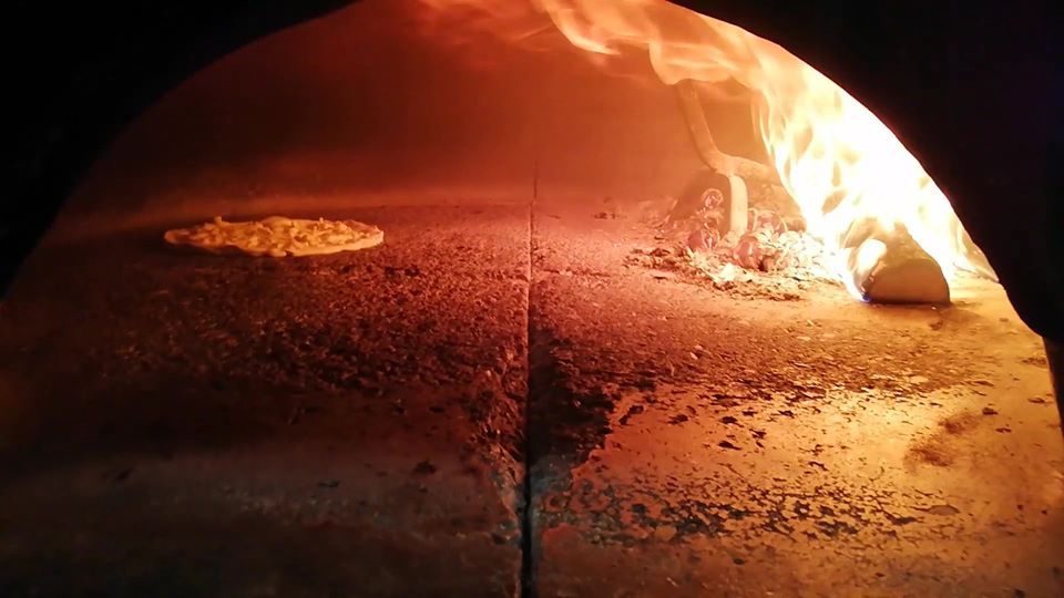 pizza in cottura nel forno a legna
