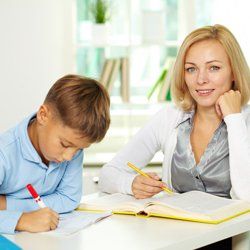 A tutor is guiding a child with his language lessons