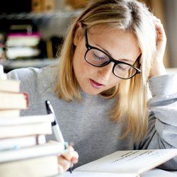 A student studying beside a stack of books