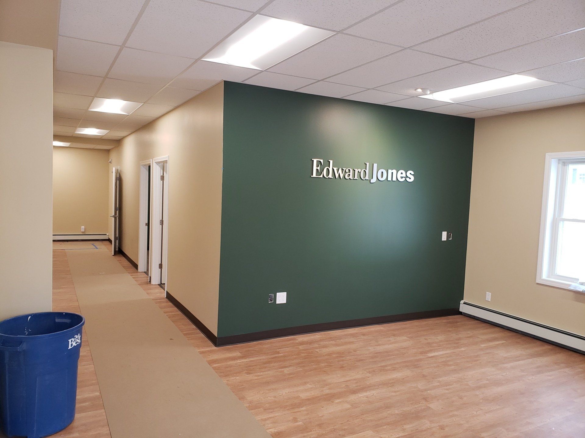 Empty office interior with green accent wall labeled “Edward Jones” and wood flooring